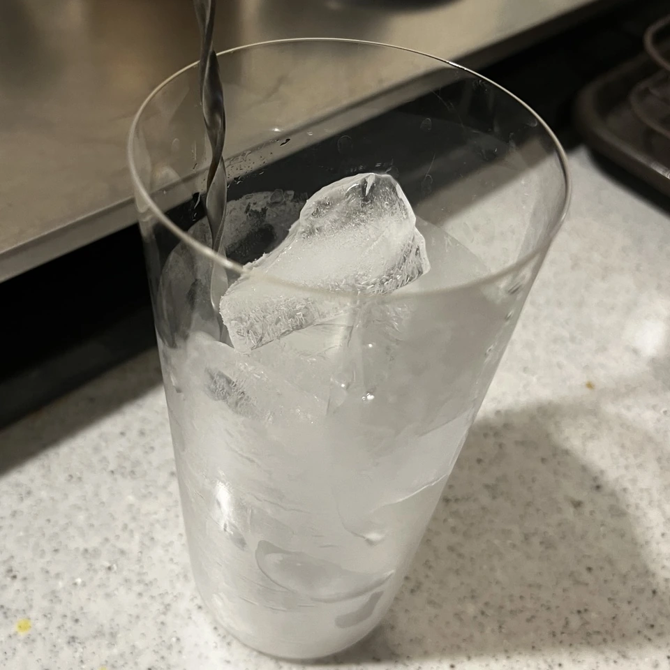 氷と少量の水を入れたグラスをマドラーで冷やしているところ