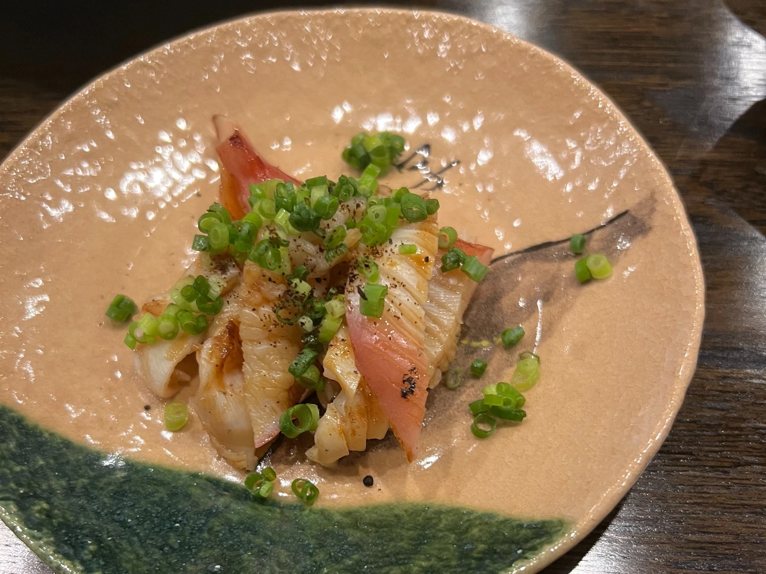 黒七味とねぎを添えた貝の炭火焼き